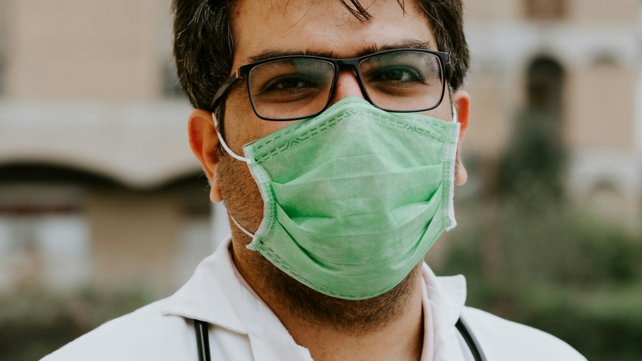 A healthcare professional wearing glasses and a surgical mask
